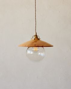 a wooden light fixture hanging from a chain on a white wall with a clear glass ball