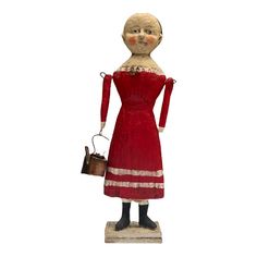 a statue of a woman wearing a red dress and holding a brown purse in her hand