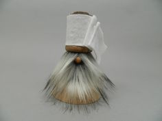 a white and grey shaving brush on top of a piece of cloth with a wooden handle