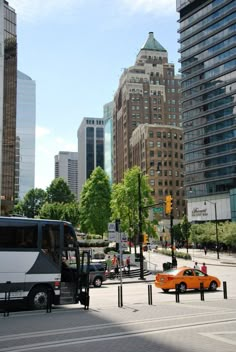 a city street with cars and buses on the road in front of tall buildings that are taller than each other