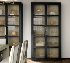 a dining room table and chairs in front of a glass cabinet with dishes on it