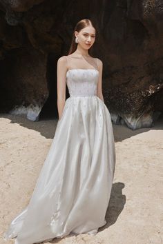 a woman in a white dress standing on the beach