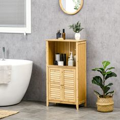 a bathroom with a bathtub, mirror and wooden cabinet next to a potted plant