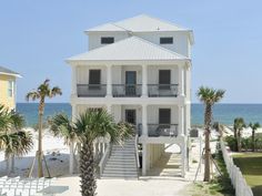 a white house on the beach with palm trees