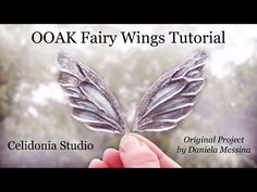 a hand holding a piece of metal with the words ooak fairy wings