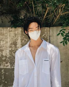 a man wearing a face mask and glasses standing in front of a wall with ivy growing on it