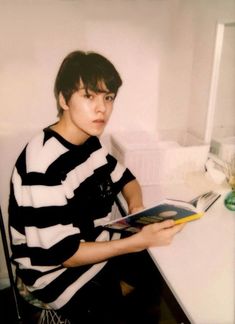 a young man sitting down reading a book