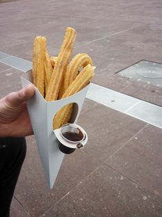 a person holding up a paper container filled with french fries