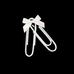 two white paper clips with a bow on it's end, against a black background