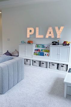 a playroom with white furniture and toys on the shelves in front of it that says play