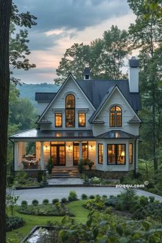 a large white house with lots of windows and plants in front of the house at dusk