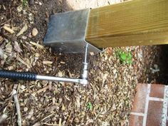 a piece of metal sitting on the ground next to a wooden post and brick walkway