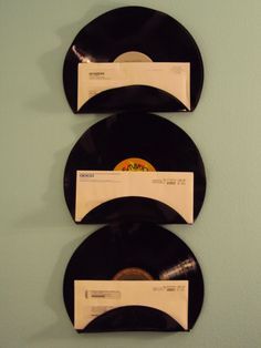 three black records are on display in front of a blue wall with white envelopes