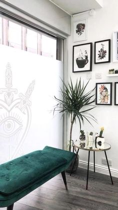 a living room with pictures on the wall and a green bench in front of it