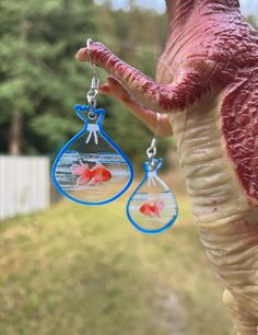 This is a very cute pair of handmade earrings. Each earring is shaped like a miniature fish tank. It is a playful and whimsical accessory, perfect for someone who loves quirky or aquatic-themed jewelry. The overall design is very ightweight. The earrings would be a fun statement piece, ideal for adding a touch of personality and a splash of color to any outfit. Protecting your earrings is important to ensure their longevity and to maintain their beauty. Here are some tips to help you protect you Blue Fish-shaped Earrings For Gift, Handmade Fish-shaped Earrings For Gifts, Blue Quirky Earrings As Gift, Quirky Blue Earrings For Gift, Quirky Blue Jewelry For Gifts, Quirky Blue Jewelry For Gift, Whimsical Accessories, Fish Earrings, Earrings Acrylic