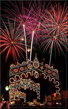 fireworks are lit up in the night sky above a building with an elaborate archway decorated with lights