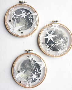 three embroidered hoops with stars and the moon in them on a white table top