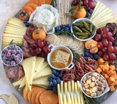 a platter filled with cheese, crackers, grapes, nuts and other foods