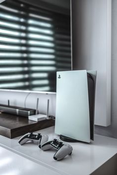 two video game controllers sitting on top of a white counter next to a large mirror