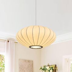 a living room with white furniture and a large light fixture hanging from the ceiling above it