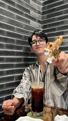 a man sitting at a table holding up a piece of pizza