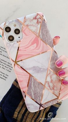 a woman's hand holding an iphone case with pink marble and gold geometric design