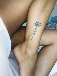 a woman with a tattoo on her arm and leg sitting in bed next to a pillow