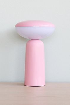 a pink vase sitting on top of a wooden table