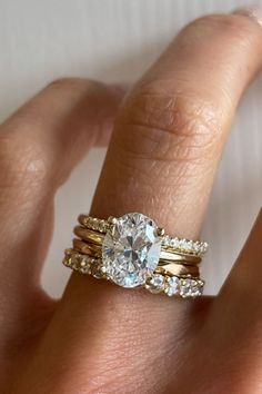 a woman's hand with two gold rings and a diamond ring on her finger