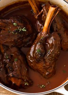 a pot filled with beef and carrots covered in gravy on top of a wooden table