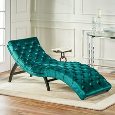 a green chaise lounge chair sitting on top of a rug