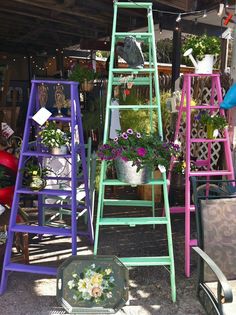 several different colored ladders with flowers and plants on them in an outdoor market area