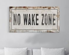 a sign that says no wake zone hanging on a wall above a couch in a living room