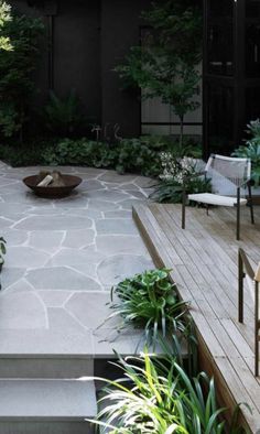 an outdoor patio with chairs and plants on the side, next to a wooden deck