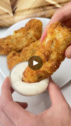 someone is dipping something into some kind of sauce on a plate with chicken tenders