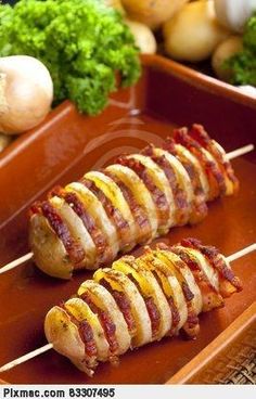 two skewered meats are sitting on a plate with vegetables in the background