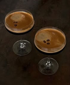 two glasses filled with liquid sitting on top of a table next to each other in front of a black background