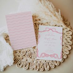 the wedding stationery is laid out on top of a doily with white and pink paper