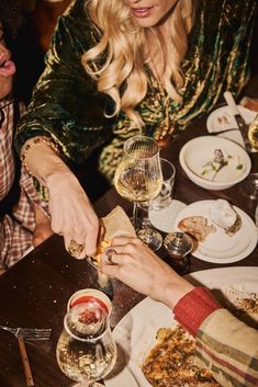 two women sitting at a table with food and drinks