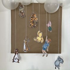 there are balloons and paper cutouts hanging from the strings with animals on them, including winnie the pooh