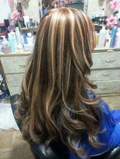 the back of a woman's head with long, wavy hair in a salon