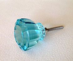 a close up of a blue glass knob on a white surface with a screwdriver