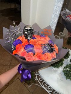 a bouquet of roses with a skull on top is being held by someone's hand