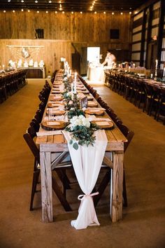 a long table set up with place settings and flowers on the tables for an event