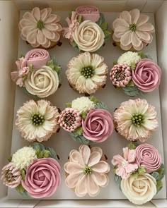 cupcakes in a box decorated with pink and white frosting flowers on top