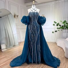 a dress on display in a room with white walls and wooden floors, including a mannequin wearing a blue gown