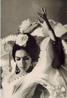 an old black and white photo of a woman with flowers in her hair wearing a dress