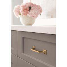 a vase with pink flowers sitting on top of a dresser