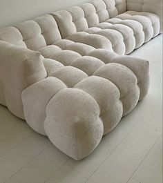 a large white couch sitting on top of a hard wood floor next to a wall