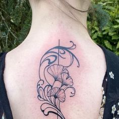 a woman's upper back tattoo with flowers on her left shoulder and an arrow in the center